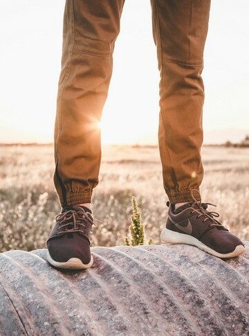 Jambes d’homme portant des chaussures nike dans un paysage ensoleillé