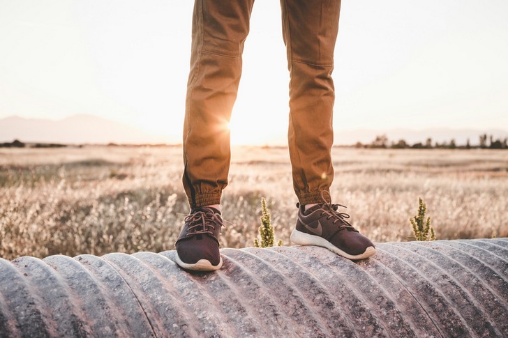 Jambes d’homme portant des chaussures nike dans un paysage ensoleillé